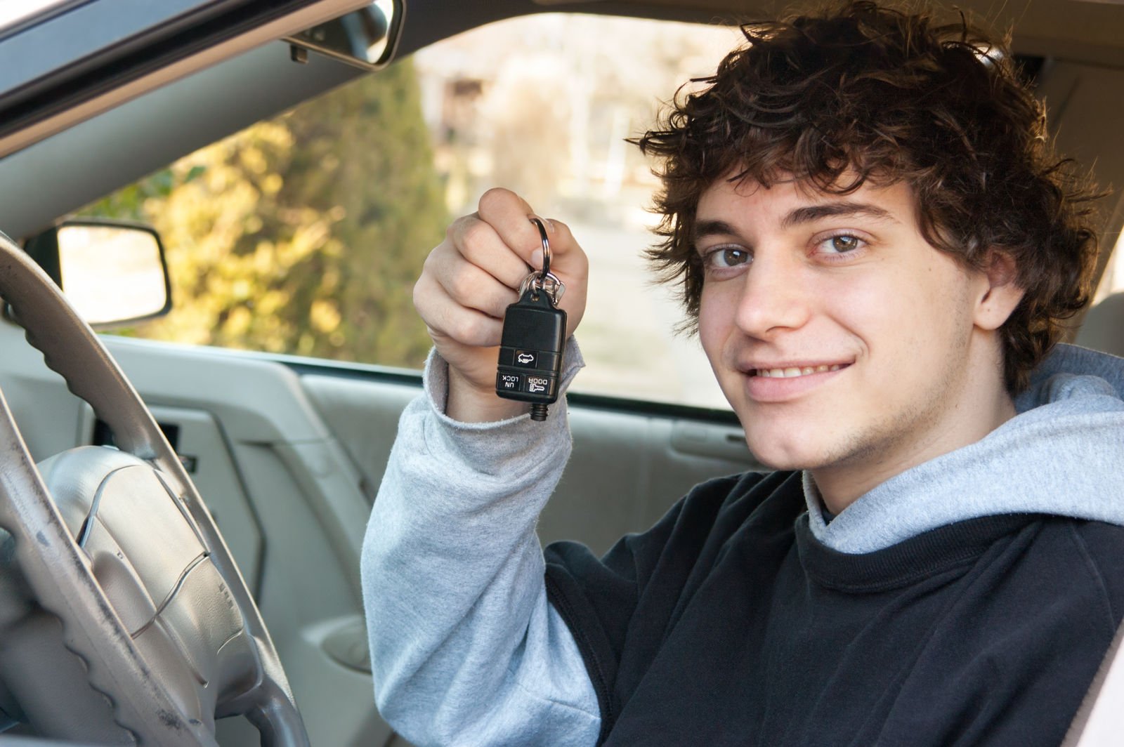 A teen boy in a car with his new keys.