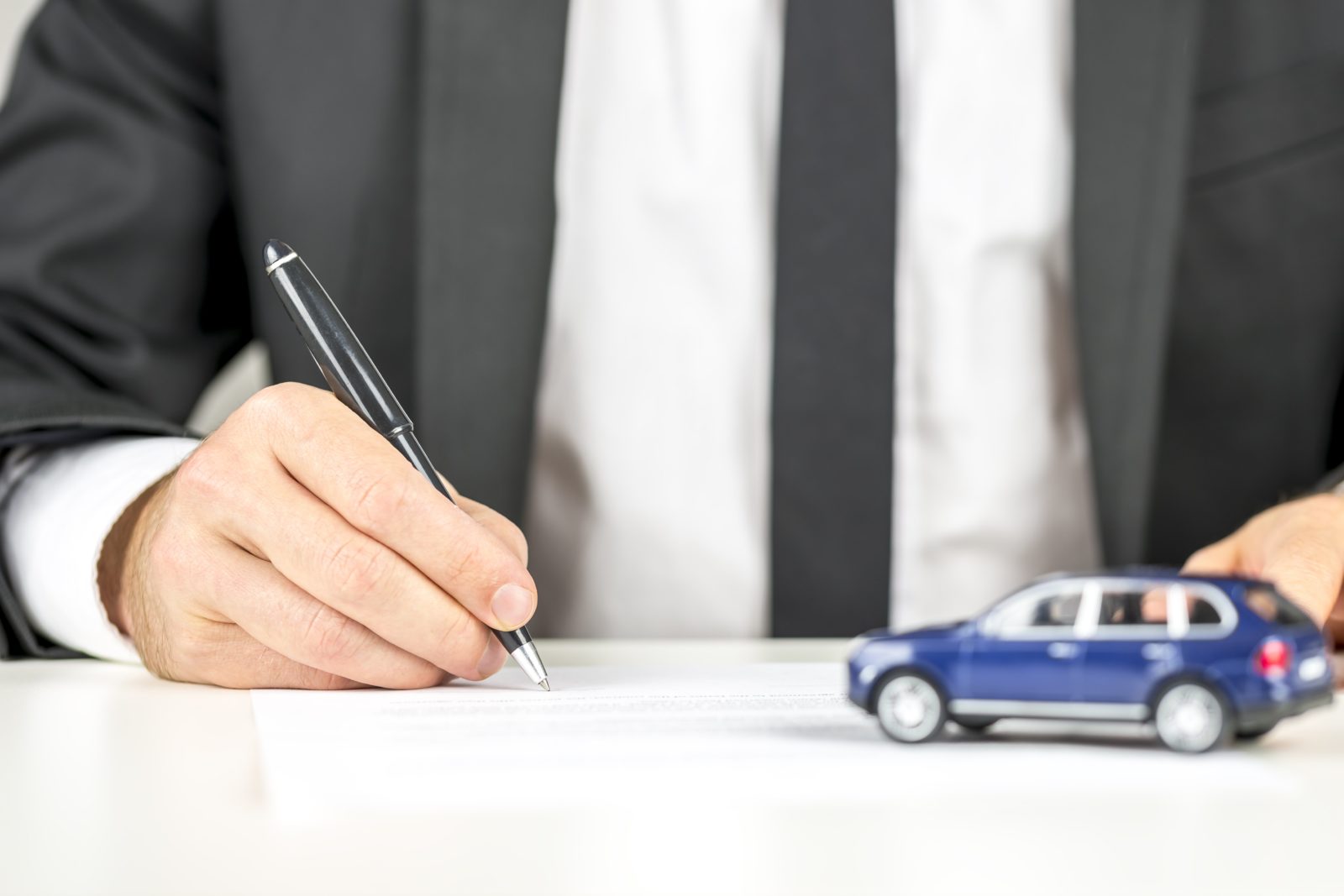 Closeup of man signing a contract of car sale.