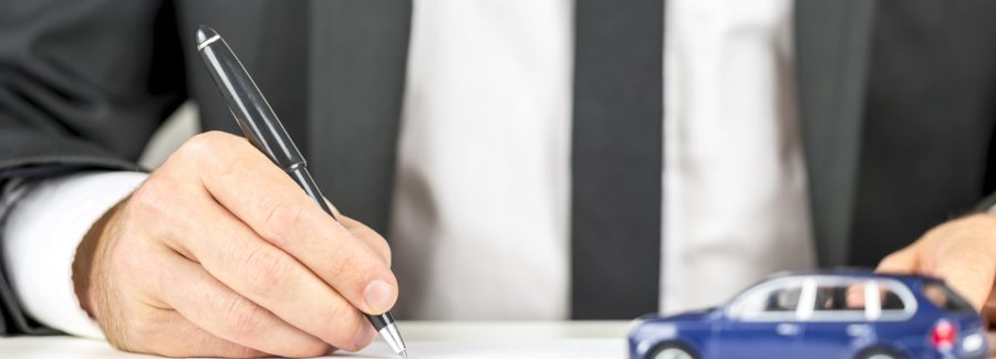Closeup of man signing a contract of car sale.