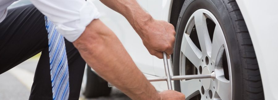 Man changing a tire, making car repair.