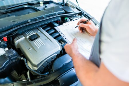 Mechanic with checklist in car workshop