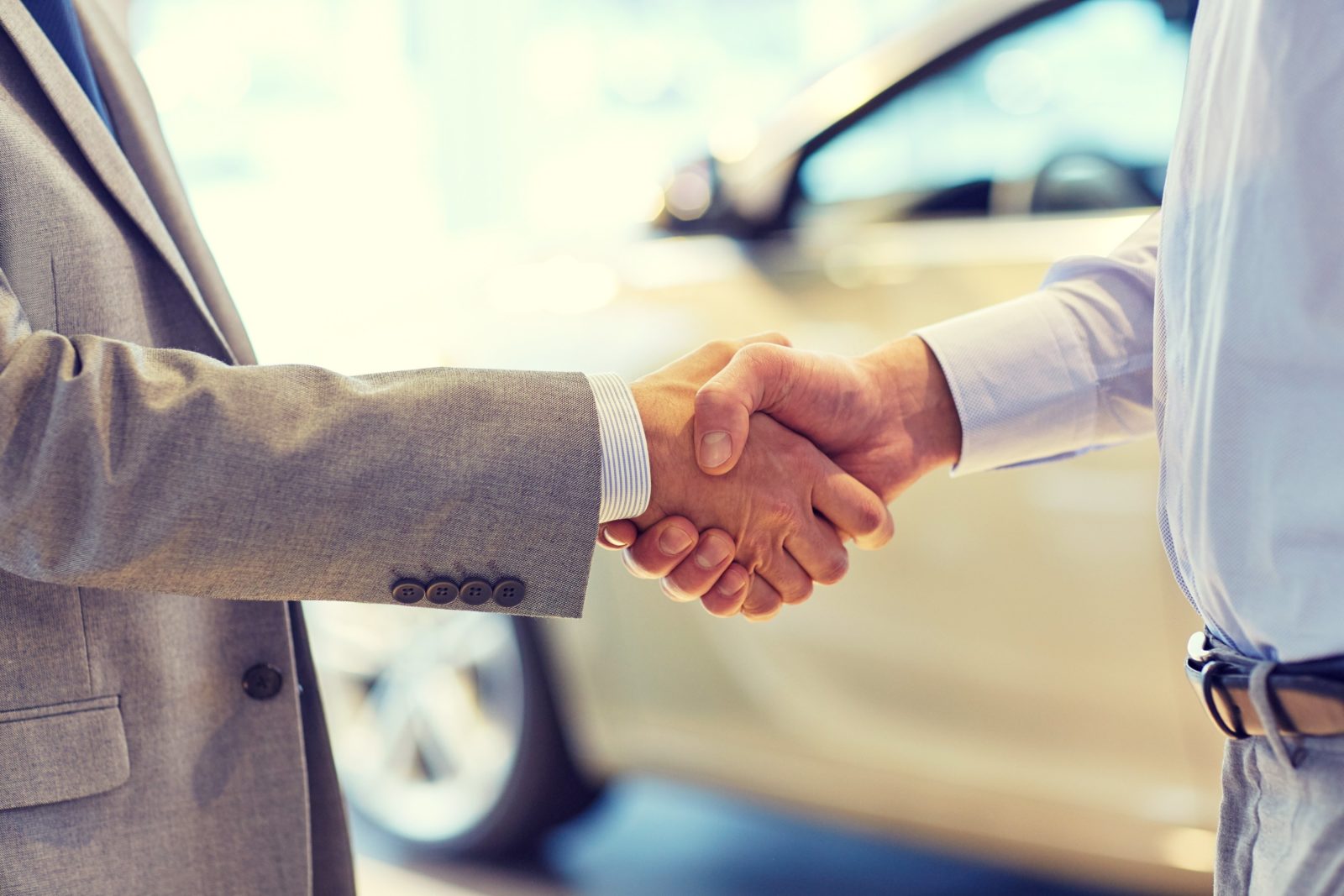 auto business, car sale, deal, gesture and people concept - close up of male handshake in auto show or salon