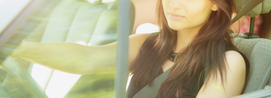 Road transportation. Beautiful young woman driver driving a car. Attractive brunette going on a trip travel.