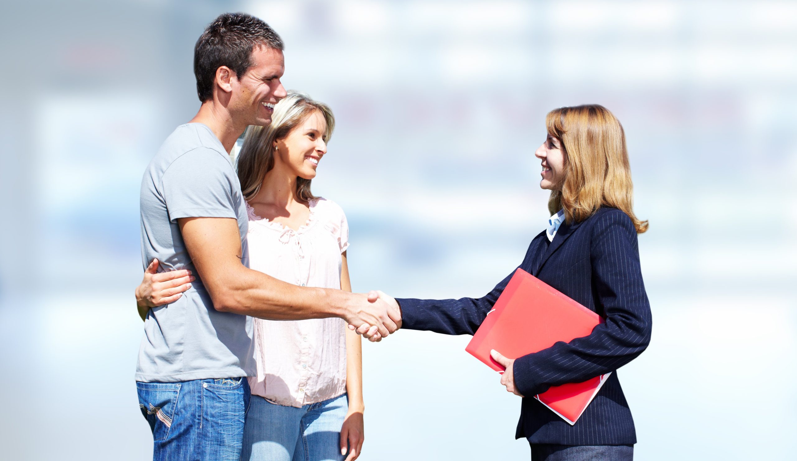 Young couple shaking hands with sales agent.