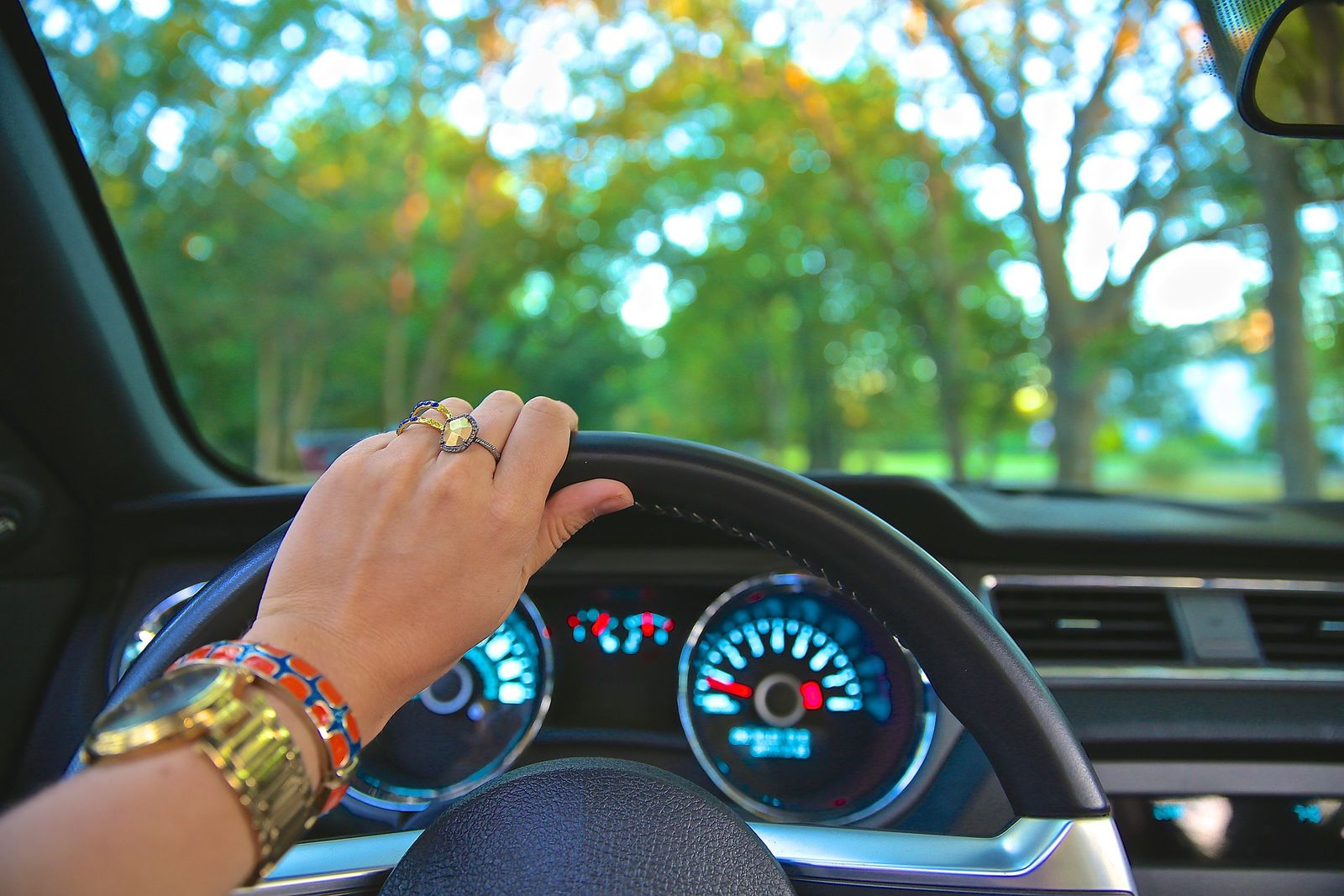 A woman driving with one hand on steering wheel.
